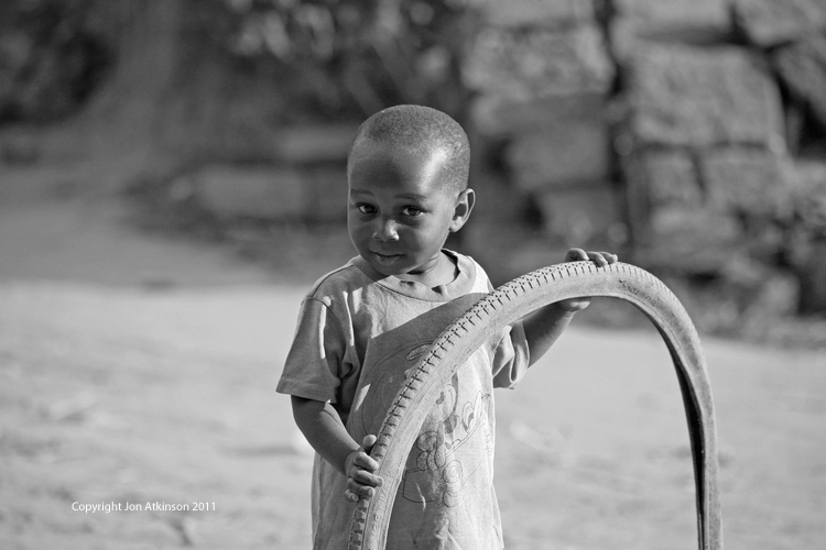 Child plays with bicycle tyre, Kenya Child plays with bicycle tyre, Kenya